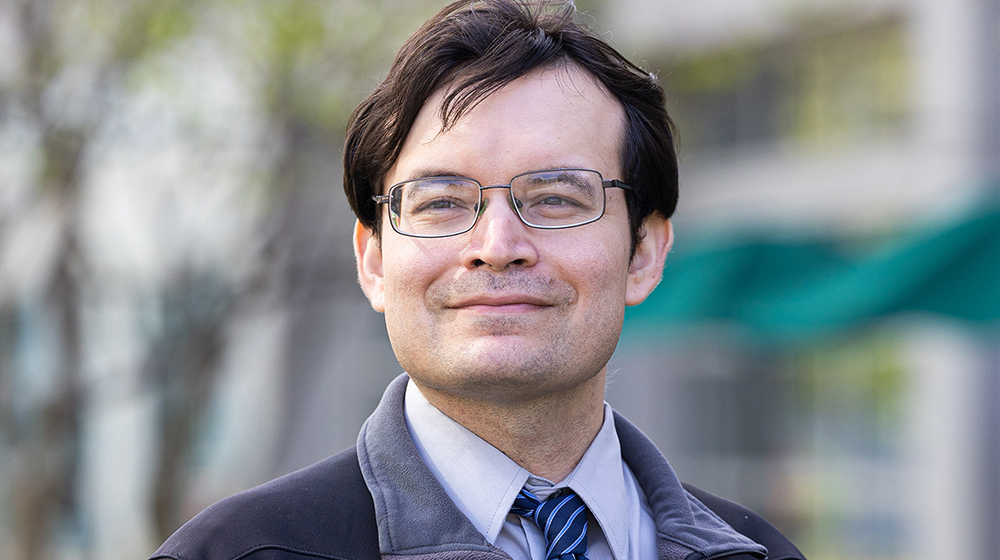 Cesar Montelongo-Hernandez wearing a collared shirt, tie, and jacket while standing outside